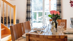 Een eethoek met een tafel voor vier personen, een vaas met bloemen en een trap naar een andere kamer.