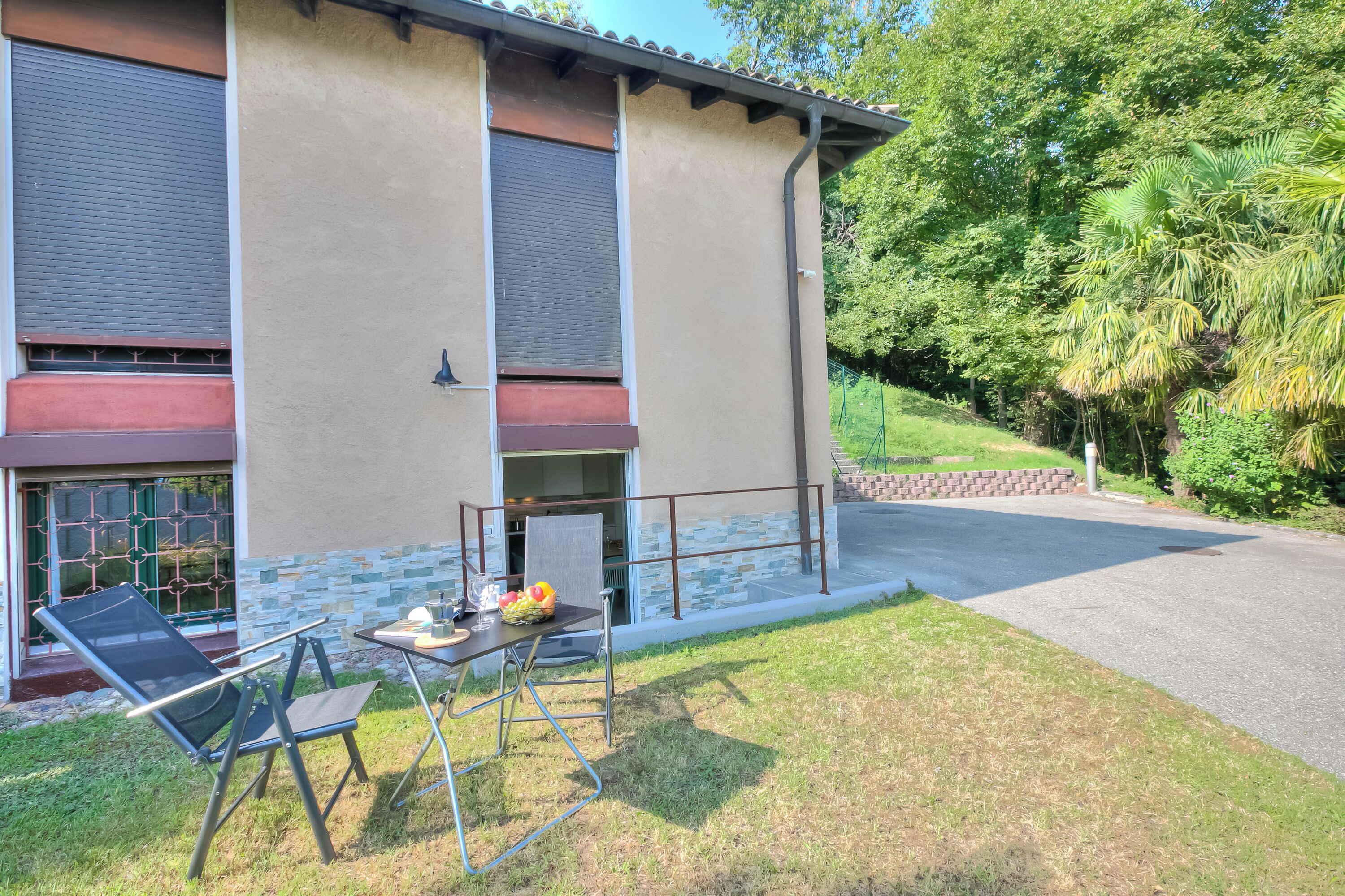 Une maison avec un patio, un barbecue et une table garnie de fruits.