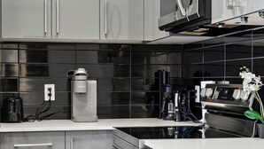 Une cuisine moderne équipée d’appareils électroménagers en acier inoxydable, d’un four à micro-ondes encastré et d’une machine à café.