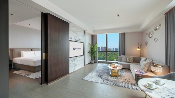 Een moderne hotelkamer met een bed, een bank, een salontafel en uitzicht op de stad.