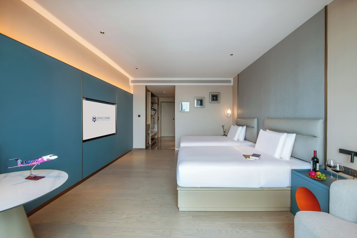 Una habitación de hotel moderna con una cama grande, una mesita pequeña y una zona de estar.
