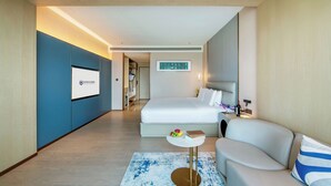 Een moderne hotelkamer met een groot bed, een zithoek en een tafeltje met een fruitschaal.