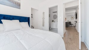 A modern hotel room with a large bed, a blue headboard, a bathroom with a mirror, and a view of a bridge. - Entire rental unit in Niagara Falls,Free parking (Niagara Falls)