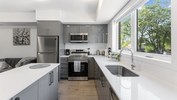A modern kitchen with stainless steel appliances, a large window, and a view of trees. - Entire rental unit in Niagara Falls,Free parking (Niagara Falls)