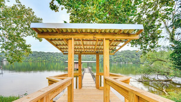 Un pontile di legno conduce a un padiglione coperto affacciato su un lago.