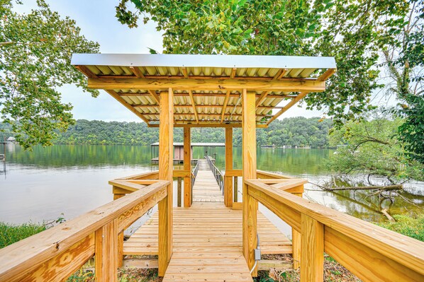 Una terraza de madera que conduce a un pabellón cubierto junto a un lago.