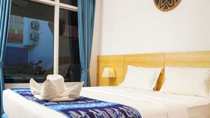 Ein Hotelzimmer mit Bett, einem Vorhangfenster, einer Wandlampe und einem Wanddekor.