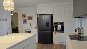 A modern kitchen with white cabinetry, a black refrigerator, and a wooden floor. - Great Family & Pet-Friendly Getaway, Sleeps 8 (Forest Lake)
