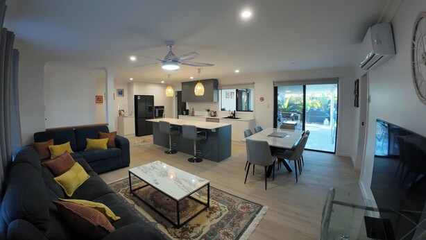 A modern living room with a sofa, coffee table, and dining area. - Great Family & Pet-Friendly Getaway, Sleeps 8 (Forest Lake)
