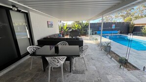 A covered patio with a pool, outdoor seating, and a view of the backyard. - Great Family & Pet-Friendly Getaway, Sleeps 8 (Forest Lake)