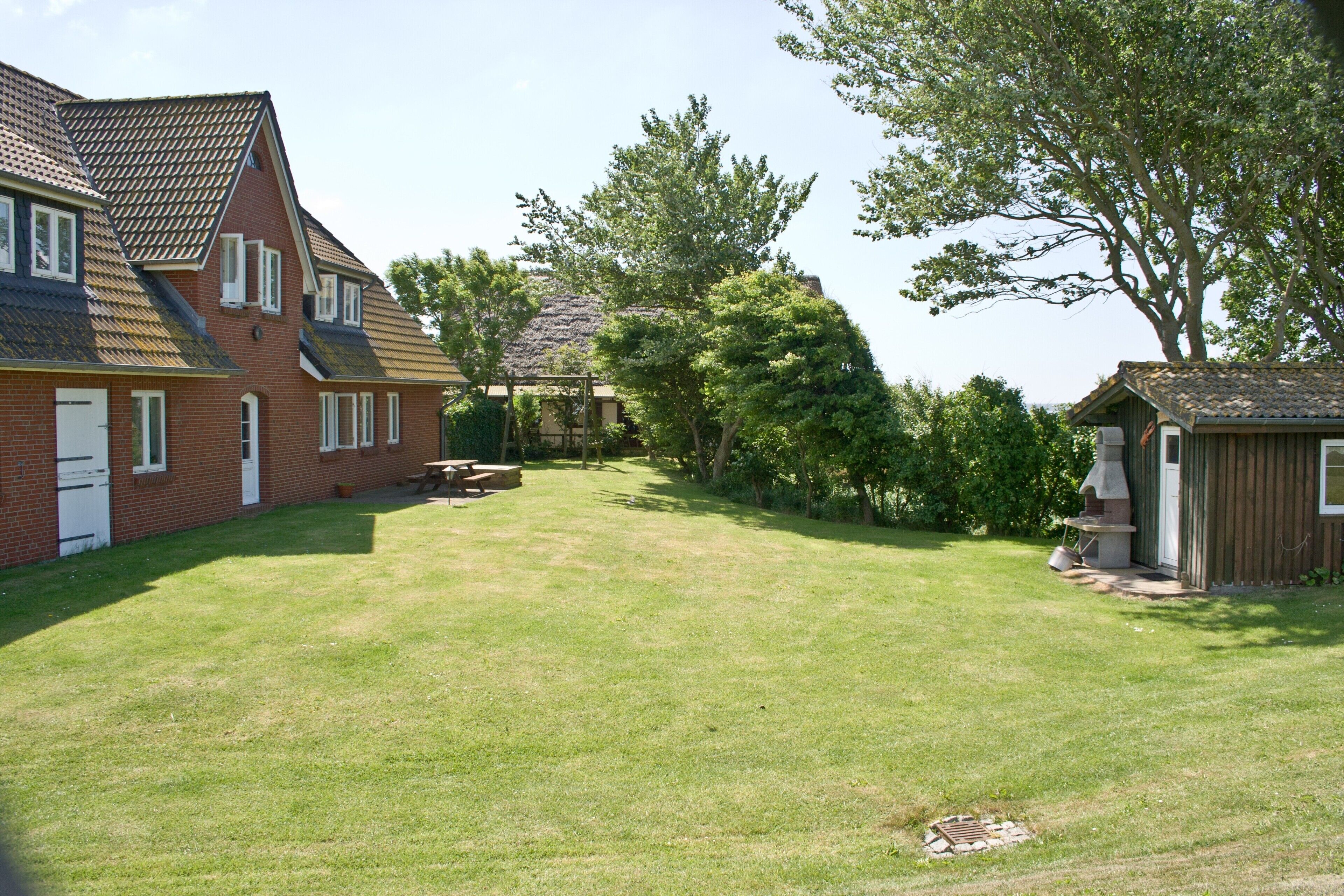 A residential property with a well-maintained lawn, a brick house, and a wooden shed.