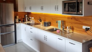 Una cocina moderna con armarios blancos, electrodomésticos de acero inoxidable y techo de madera.