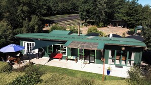 Un edificio con techo verde, un patio, mesas al aire libre y vistas a campos en terraza al fondo.