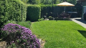 Un jardín bien cuidado con césped, setos y plantas con flores.