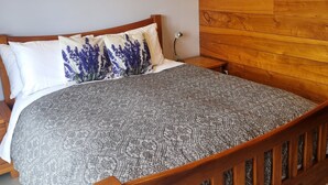 Una cama de madera con una colcha estampada, una mesita de noche y un cuadro colgado en la pared.