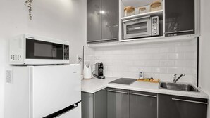 Une cuisine moderne équipée d’un réfrigérateur blanc, d’un four à micro-ondes, d’une machine à café et d’un évier.