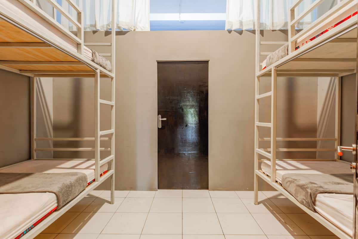 A dormitory room with bunk beds, a door, and a tiled floor.