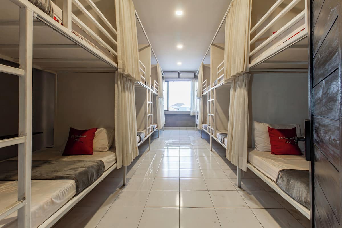 A corridor with bunk beds, each with a pillow and a blanket.