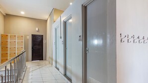 A hotel corridor with lockers, a shower room sign, and numbered hooks on the wall. - Collection O Seminyak Near Seminyak Beach Formerly De Shabach (Legian)