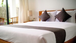 Una cama bien hecha con ropa de cama blanca y marrón, un cabecero de madera y una mesita de noche con lámpara.