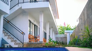 Un edificio moderno con piscina, asientos exteriores y una escalera que sube a los pisos superiores.