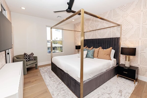 A modern bedroom with a four-poster bed, a desk, a chair, and a nightstand with a lamp. - A Desert Dream | Perfect Getaway in Old Town! (Scottsdale)
