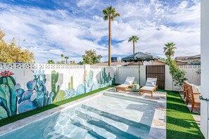 A swimming pool with a mural of cacti, two lounge chairs, and a wooden deck. - A Desert Dream | Perfect Getaway in Old Town! (Scottsdale)