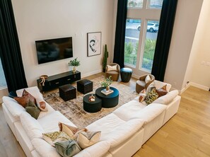 A modern living room with a large sectional sofa, a flat-screen TV, a coffee table, and a sideboard. - A Desert Dream | Perfect Getaway in Old Town! (Scottsdale)