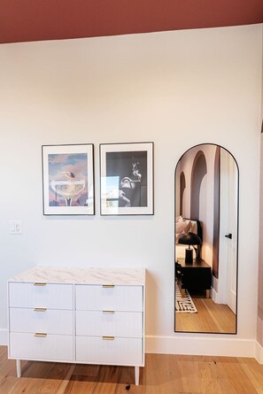 A room with a white dresser, two framed artworks, and a mirror reflecting a bed and a lamp. - A Desert Dream | Perfect Getaway in Old Town! (Scottsdale)