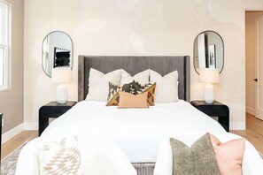 A bedroom with a large bed, two bedside tables with lamps, and two round mirrors on the walls. - A Desert Dream | Perfect Getaway in Old Town! (Scottsdale)