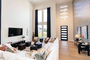 A modern living room with a large sofa, a flat-screen TV, and a coffee table.