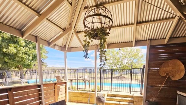 A covered patio with a table and chairs, a hanging light fixture, and a view of a swimming pool. - Trawalla - an entire house & pool bar - GREAT FOR GROUPS (Gundaroo)