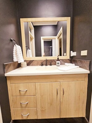 A bathroom with a wooden vanity, a large mirror, and a sink.