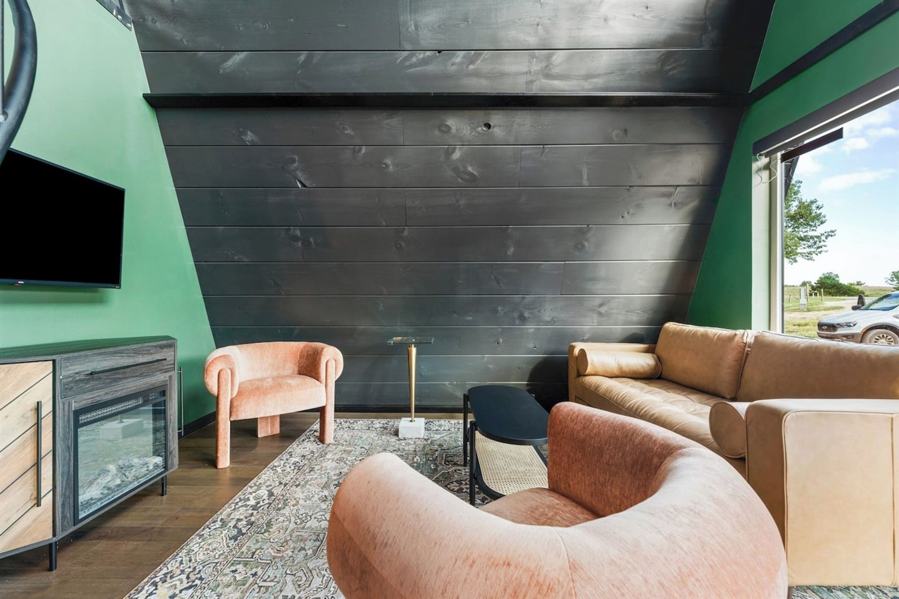 A modern living room with a large black wall, a flat-screen TV, and a mix of seating including a sofa and armchairs.
