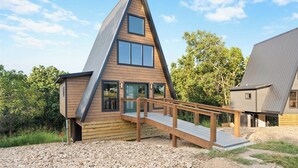Uma casa moderna no estilo A, com fachada de madeira, um deck de madeira e um caminho de acesso de cascalho.