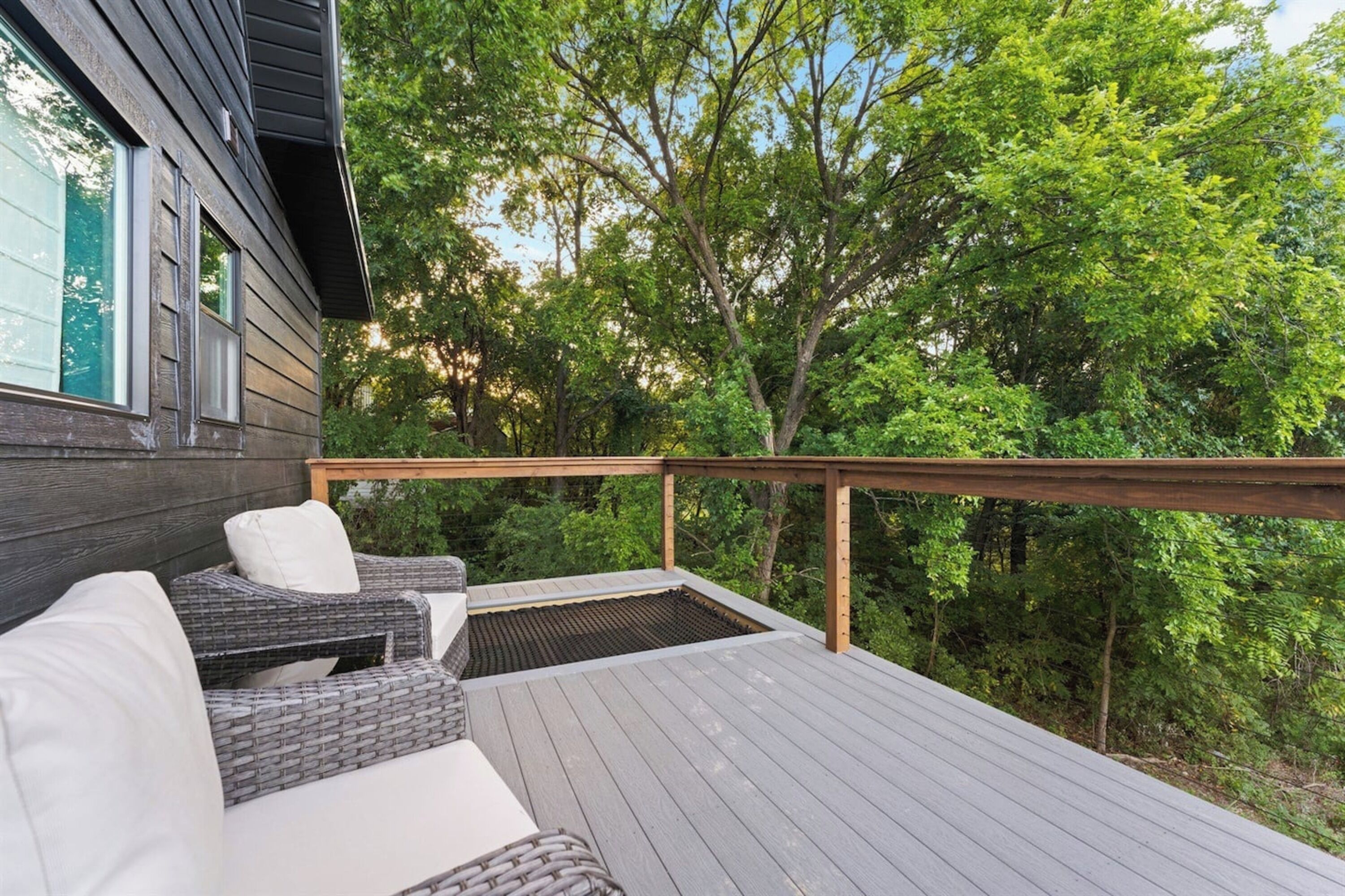 Une terrasse en bois, dotée de mobilier d’extérieur et offrant une vue sur une forêt.