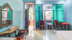 A room with a bed, two wooden chairs, a small table, a mirror, and a window with curtains. - Hotel O Danawa House  (Denpasar)