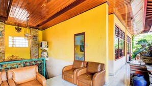 A room with a yellow wall, a wooden ceiling, and a stone wall. There is a window, a door, and a bench. - Hotel O Danawa House  (Denpasar)