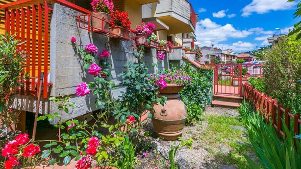 A residential building with a balcony, potted plants, and a garden area. - Beautiful apartment for 5 guests with WIFI, TV and patio (Greve In Chianti)