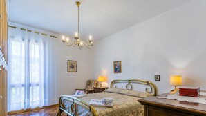A bedroom with a bed, two bedside tables with lamps, a chandelier, and a wooden floor. - Beautiful apartment for 5 guests with WIFI, TV and patio (Greve In Chianti)