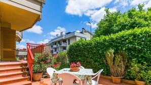A patio with a table and chairs, surrounded by potted plants and a hedge. - Beautiful apartment for 5 guests with WIFI, TV and patio (Greve In Chianti)