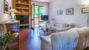 A living room with a sofa, a TV, a fireplace, and a bookshelf. - Beautiful apartment for 5 guests with WIFI, TV and patio (Greve In Chianti)