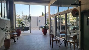 An indoor seating area with large windows, potted plants, and a sign for 'Mokosh'. - Mythical Sands- HANA (Protaras)