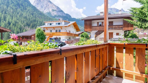 A wooden balcony with a view of a mountain and a building with a balcony.