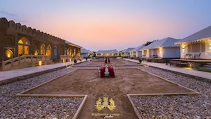 Un complex turístic al desert amb tendes i un edifici gran amb finestres d'arc.