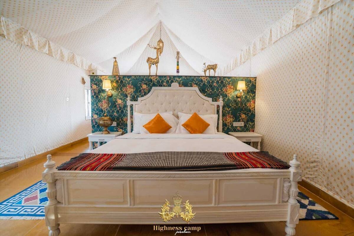 Una amplia habitación con tienda, una cama grande, un cabecero ornamentado y apliques decorativos en las paredes.