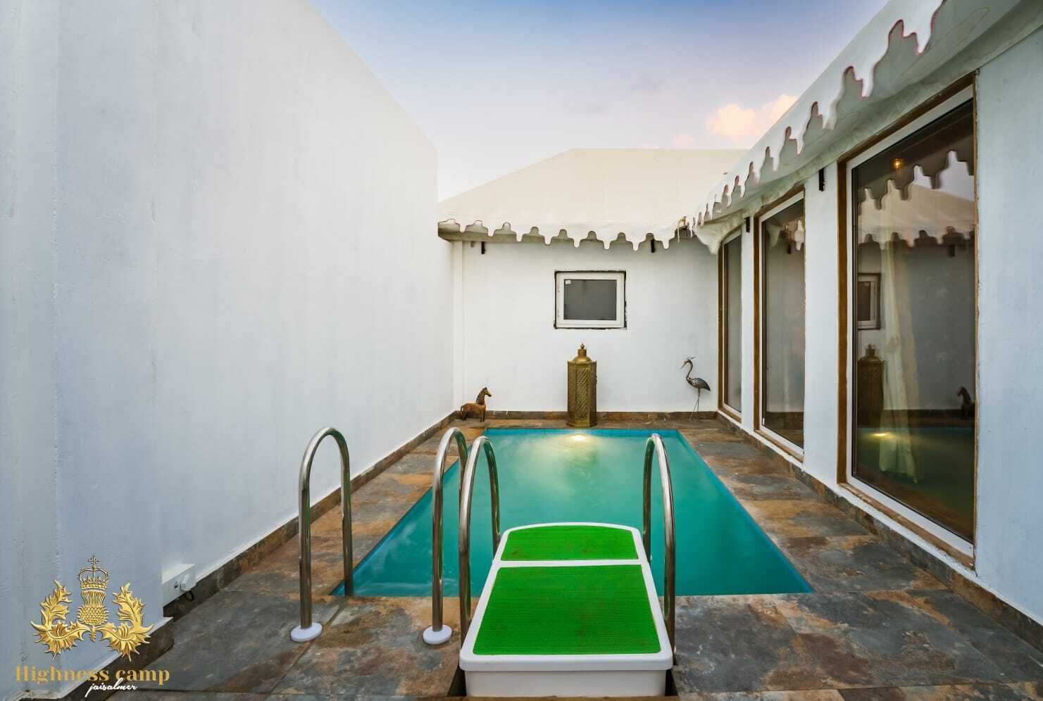 Una piscina con cubierta verde, rodeada de paredes blancas y suelo de baldosas.