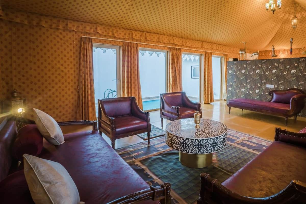 Una habitación amplia con techo estampado, sofás de cuero, sillones y una mesa de centro redonda.