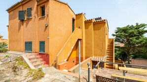 Un edificio con una escalera que lleva a una puerta, un ventanal pequeño y una barandilla metálica.