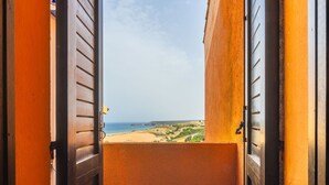 Un balcón con vista a una playa y colinas lejanas.